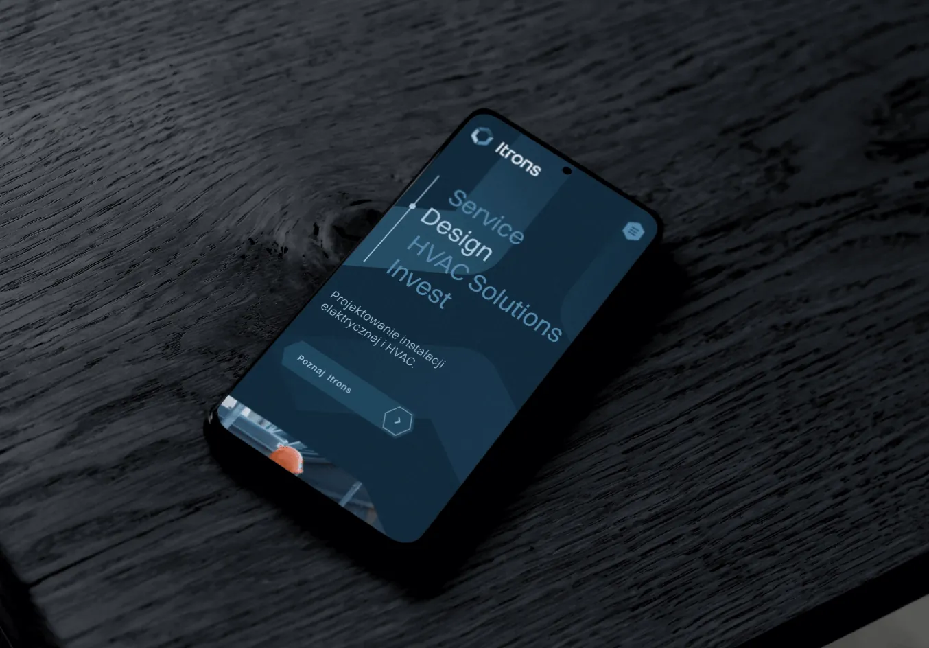 Telefon z listą usług Itrons na ciemnym drewnianym blacie.