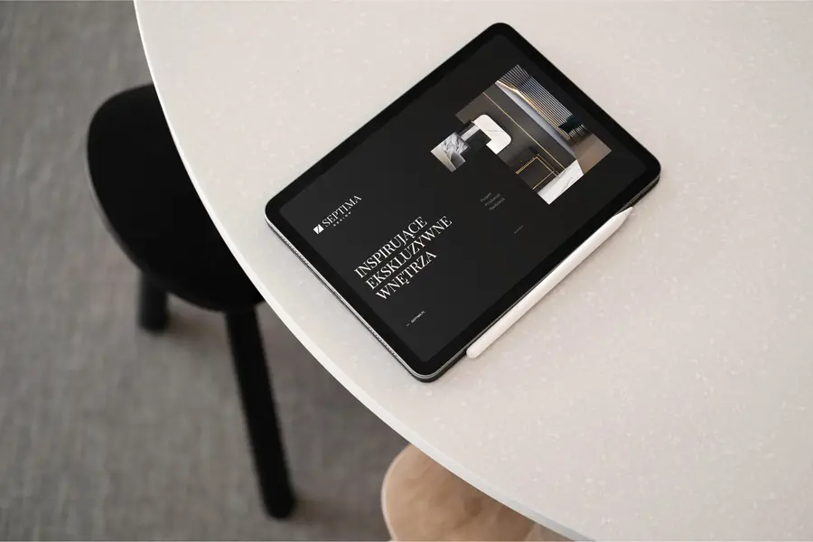 Tablet ze stroną główną Septima Design na okrągłym białym stoliku.
