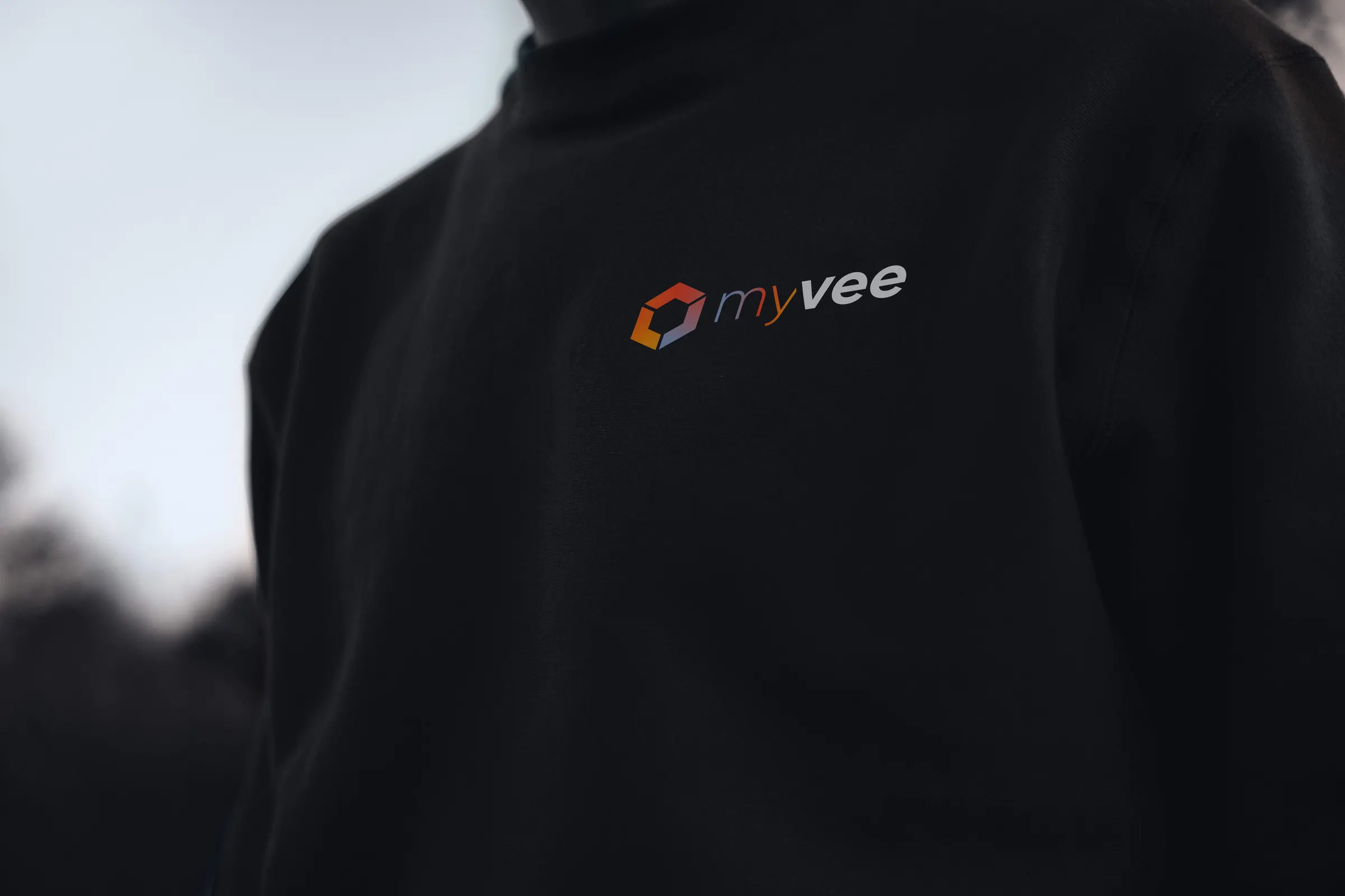 Czarna bluza z gradientowym logo myvee na piersi.