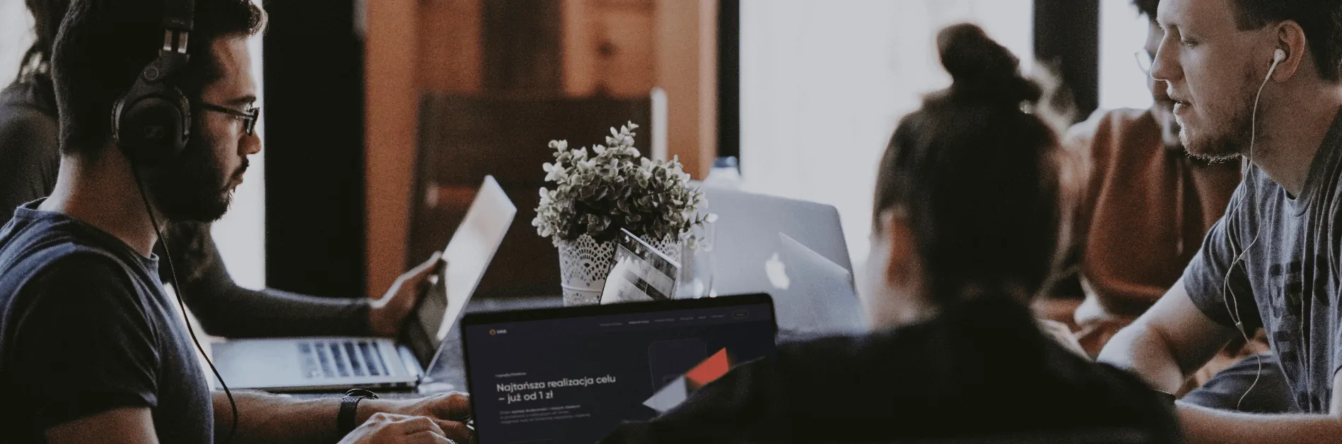 Zespół przy stole z laptopami, na ekranie strona Vee.