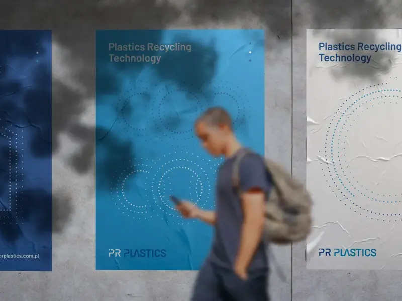 Plakaty PR Plastics „Plastics Recycling Technology” na ścianie w mieście, obok przechodzi mężczyzna z telefonem.